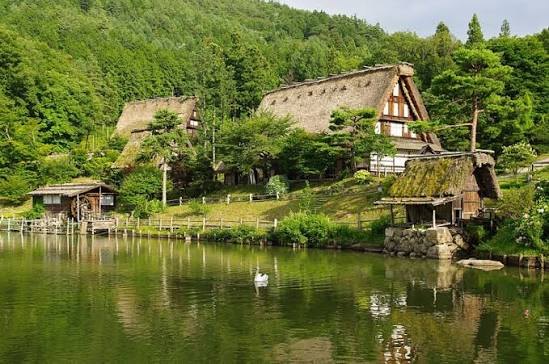 Boerderijen met rieten daken aan een vijver in het openluchtmuseum Hida no Sato