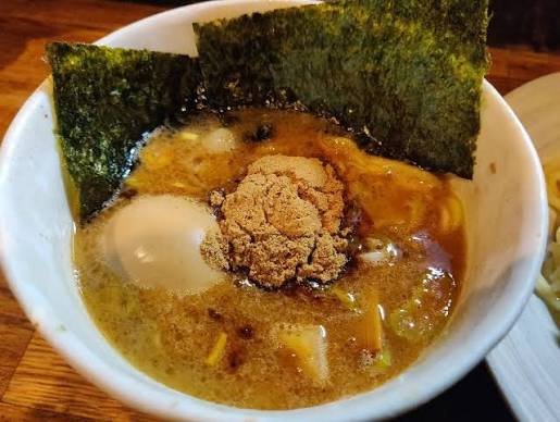 Een kom tsukemen bouillon met een ei, nori en vispoeder