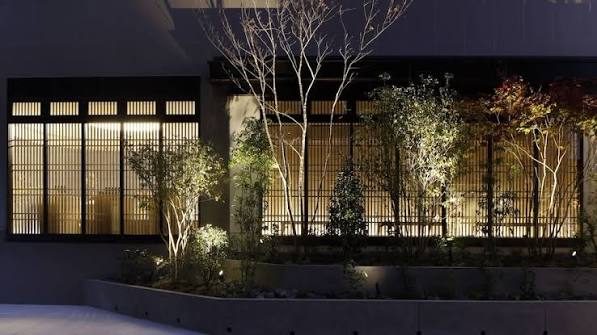 De verlichte gevel en de tuin van Soki Kanazawa bij avond