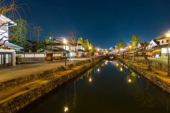 Het kanaal van Bikan in Kurashiki bij avond, met de witte pakhuizen weerspiegeld in het water